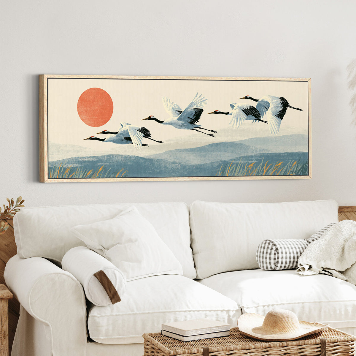 red crowned cranes flying over canvas wall art in an oak finish floater frame in a styled room setting