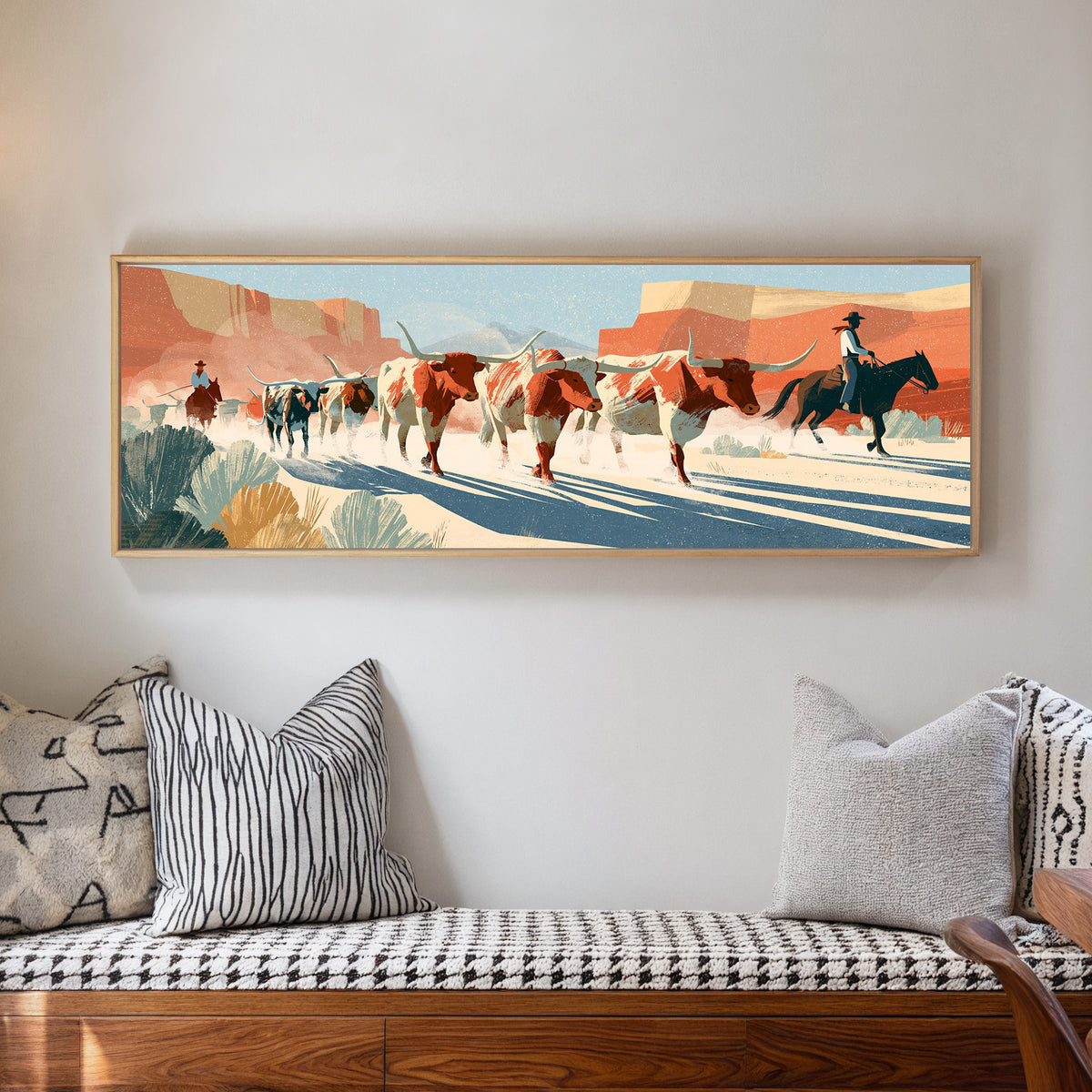 longhorn cattle and mounted riders beneath canvas wall art in a natural floater frame in a living room