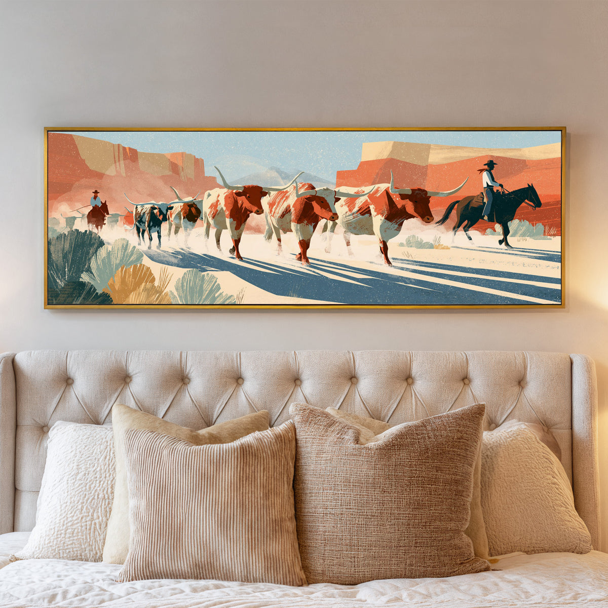 longhorn cattle and mounted riders beneath canvas wall art in a gold floater frame above a bed