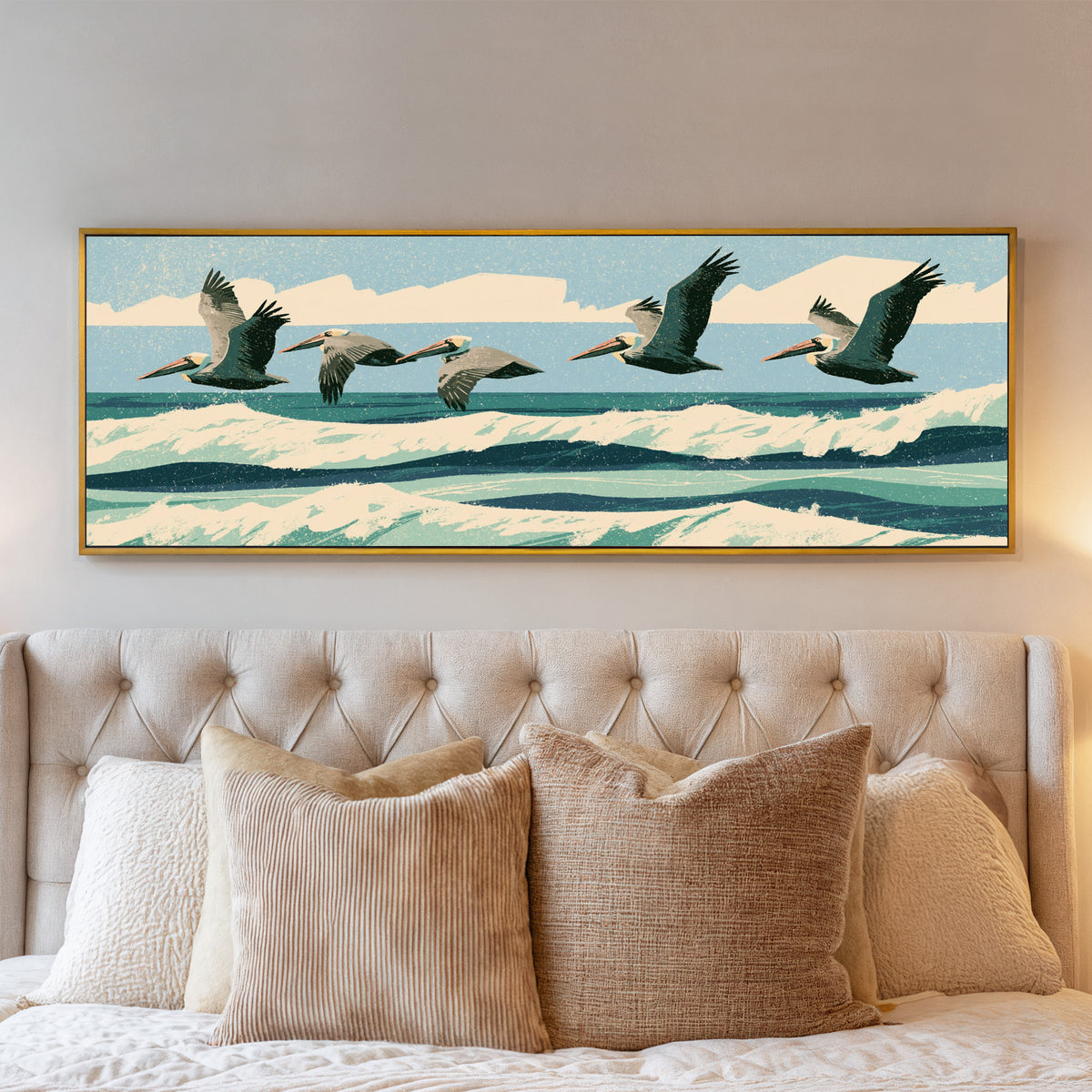 five brown pelicans flying over teal surf canvas wall art in a gold floater frame above a bed