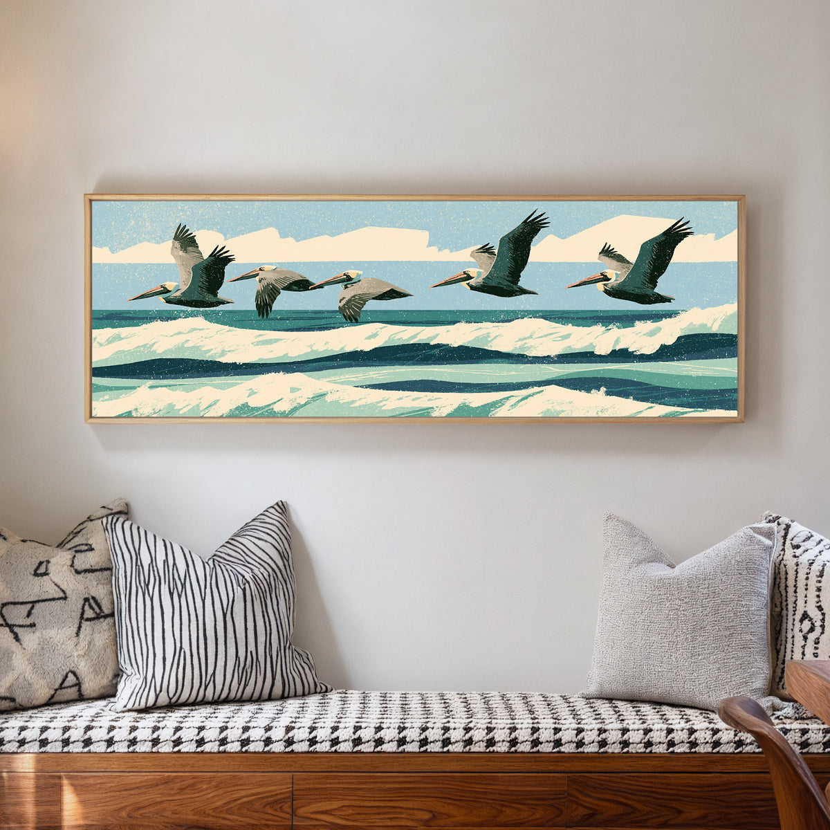 five brown pelicans flying over teal surf canvas wall art in a natural floater frame in a living room