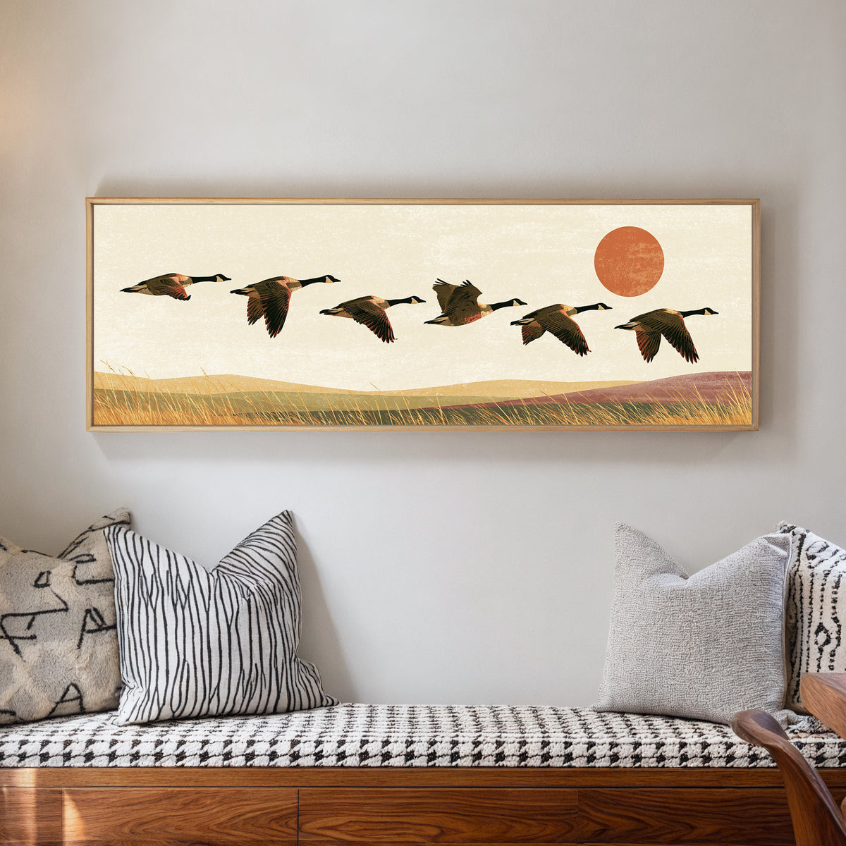 six canada geese flying over golden grass canvas wall art in a natural floater frame in a living room
