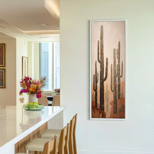This vertical canvas wall art features a desert landscape with saguaro cacti in a warm palette of browns and oranges, set against a textured background and framed in white on.