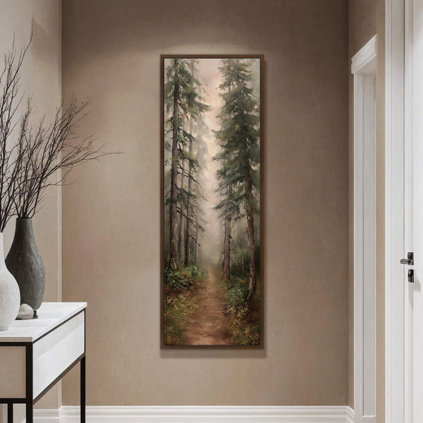 A vertical canvas print showcases an impressionistic forest path with tall pine trees and lush greenery, framed in dark wood and displayed on a neutral, textured wall above a console.