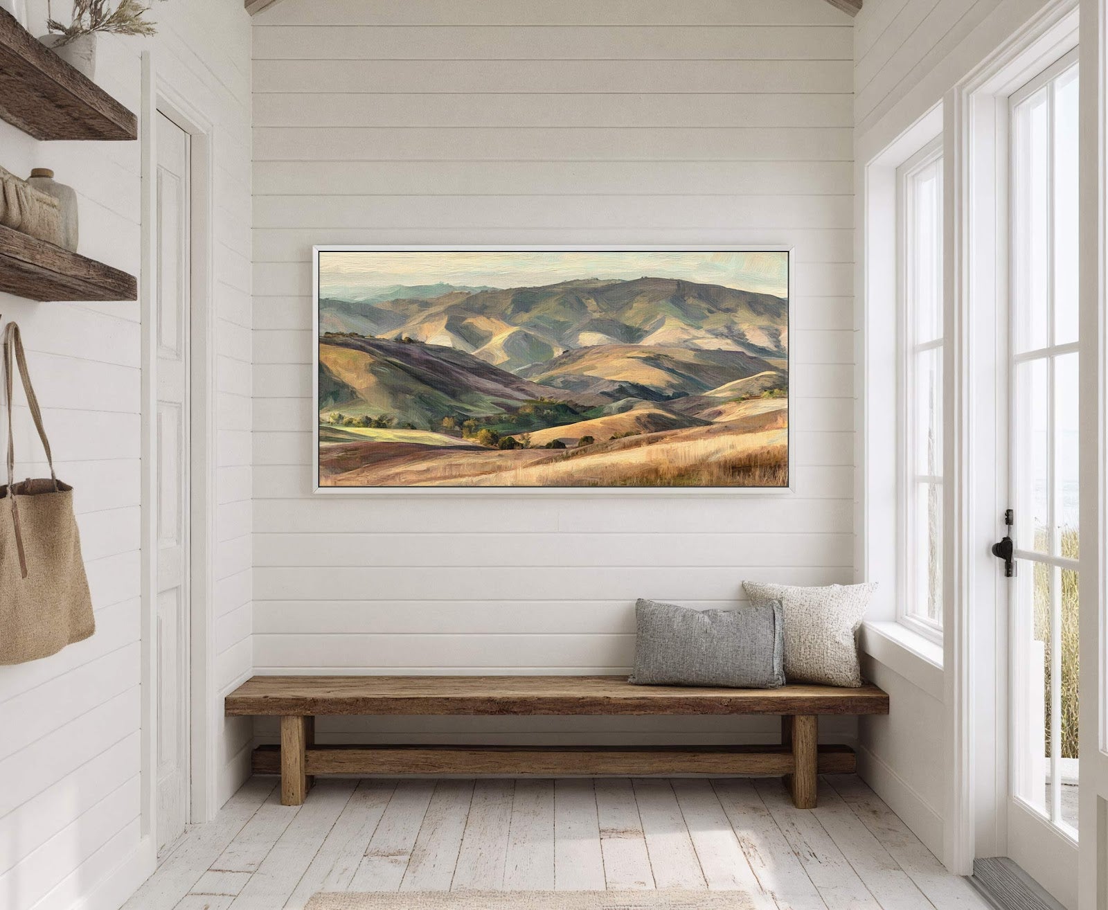 This horizontal canvas wall art depicts rolling hills with a muted green and tan palette in an impressionistic style, displayed on a white shiplap wall above a rustic wooden bench.