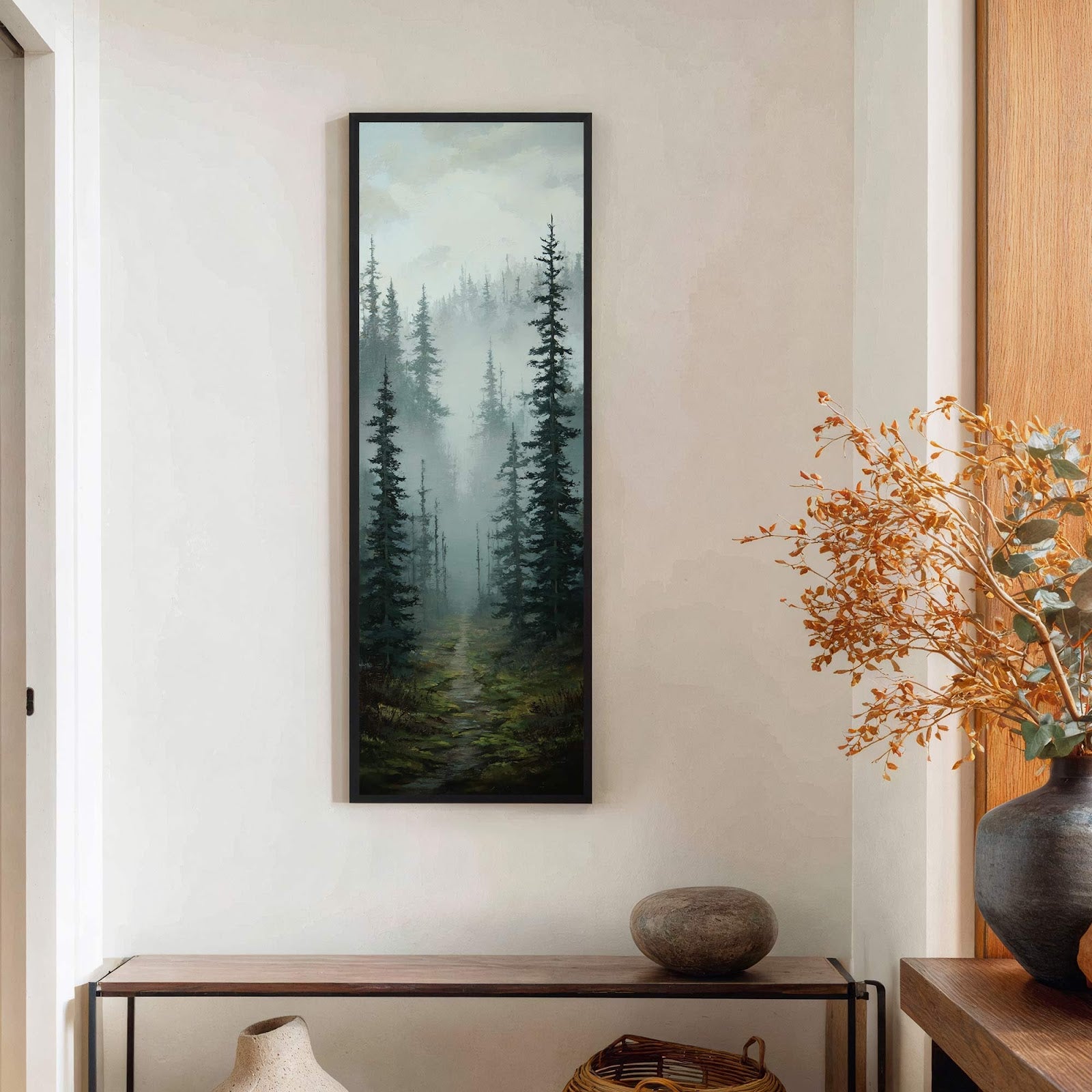 This vertical, oil painting print in a black floater frame depicts a misty forest scene with dark green trees and a mossy path. It hangs on a light-colored wall above.