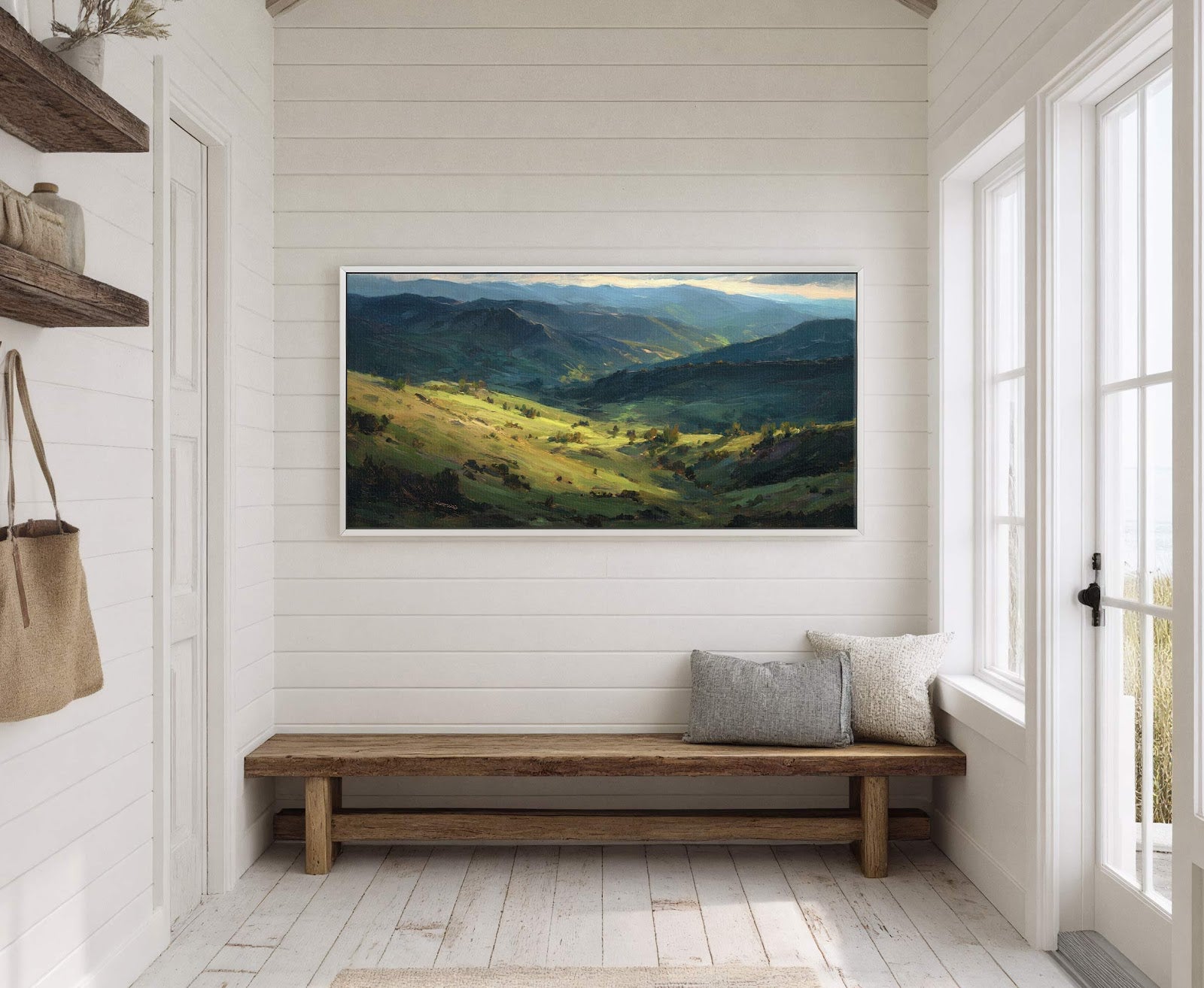 This horizontal landscape painting print features rolling green hills and distant mountains under a soft blue sky, rendered in a realistic impressionistic style. It hangs on a white paneled wall.