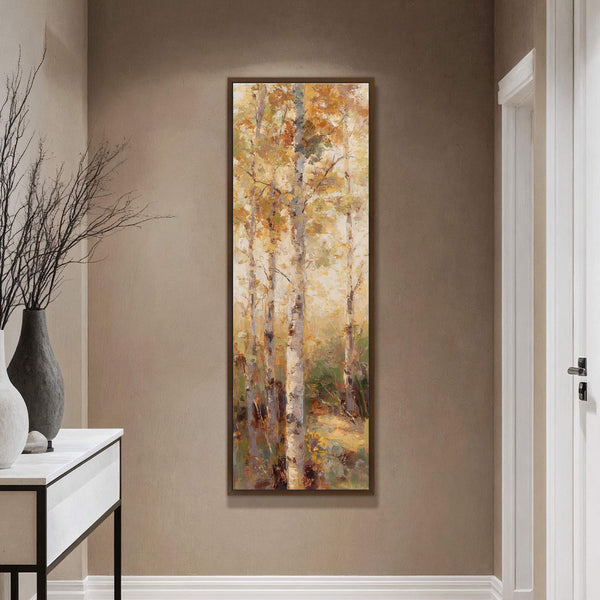 Vertical canvas wall art featuring an impressionistic forest scene with birch trees and a warm yellow-orange palette, set against a taupe wall with a white console table and vase on.