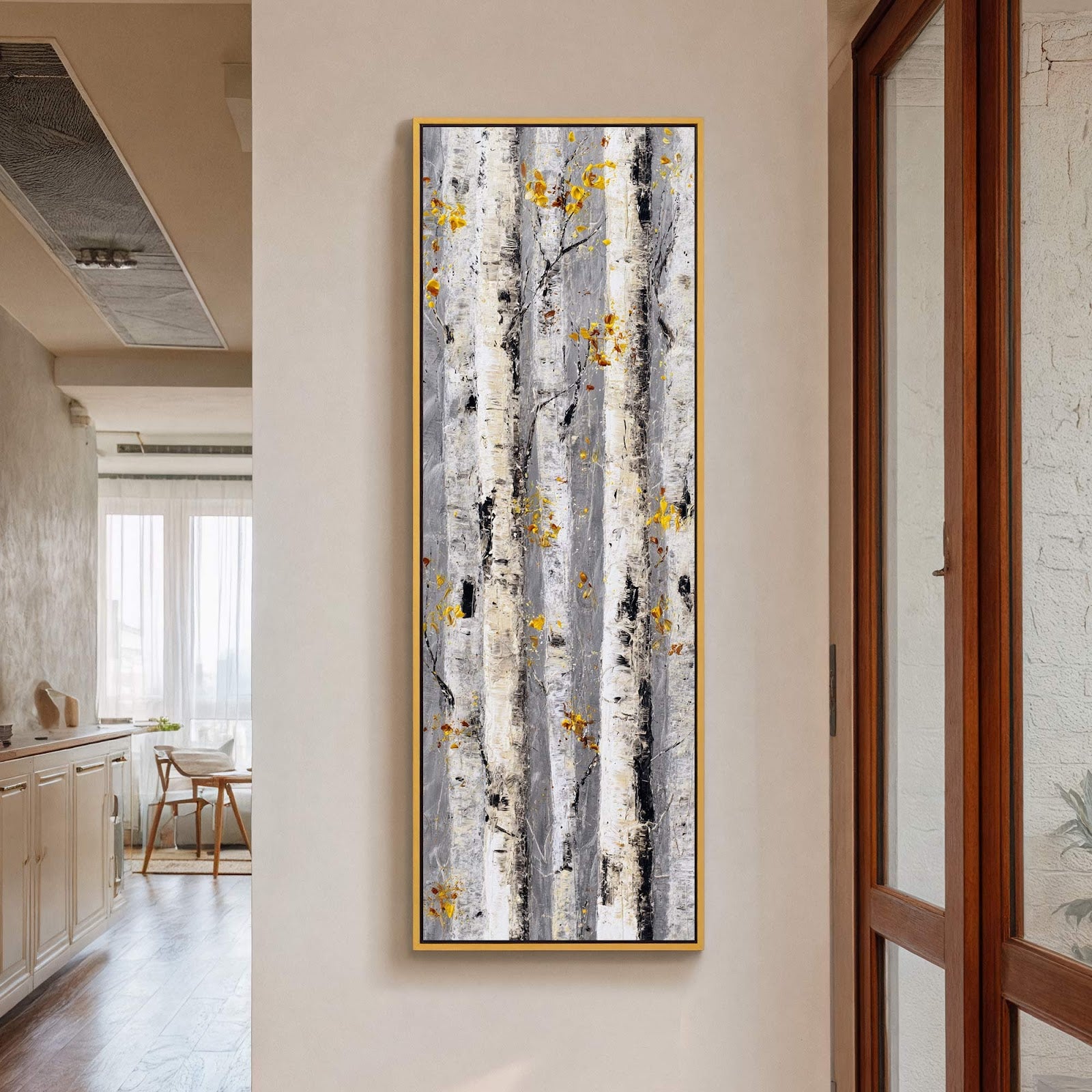 This vertical, abstract canvas wall art features a textured depiction of birch trees in a monochromatic palette with subtle yellow accents, framed in gold, and hung on a neutral wall.