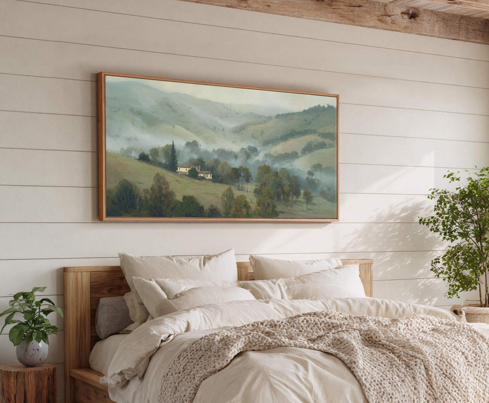 This horizontal canvas wall art features a serene landscape with rolling hills and a distant house, rendered in a muted green and blue palette. It hangs above a bed against.