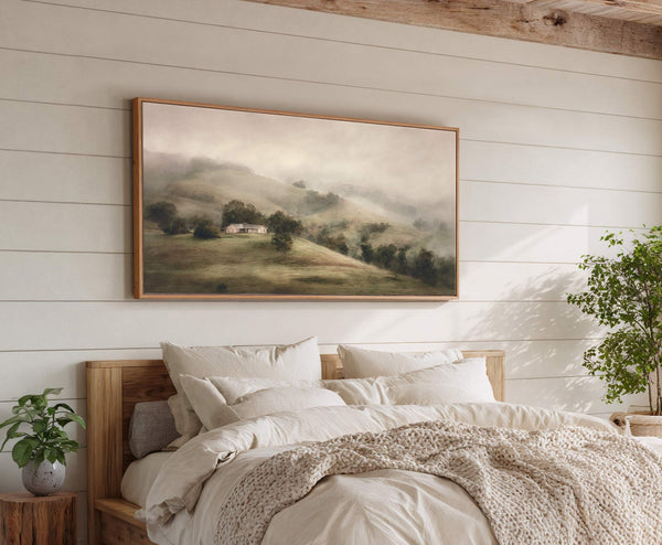 This horizontal canvas wall art features a serene misty landscape with rolling hills and a distant house, rendered in a soft, muted palette and impressionistic style. It is displayed above.