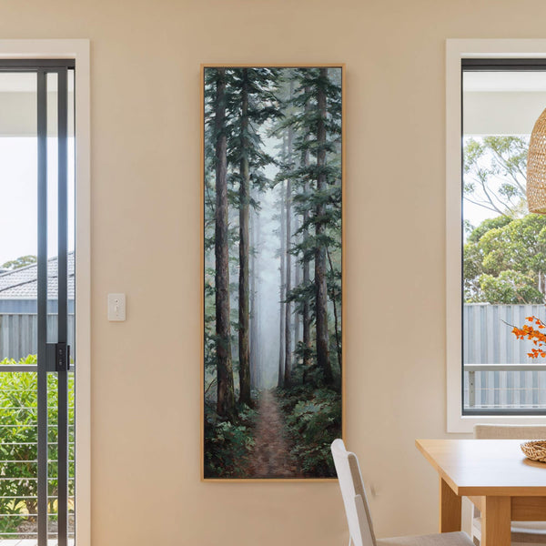 This vertical canvas print features a misty forest scene with tall evergreen trees and a winding path, rendered in a realistic style with a cool, muted palette, displayed on a.