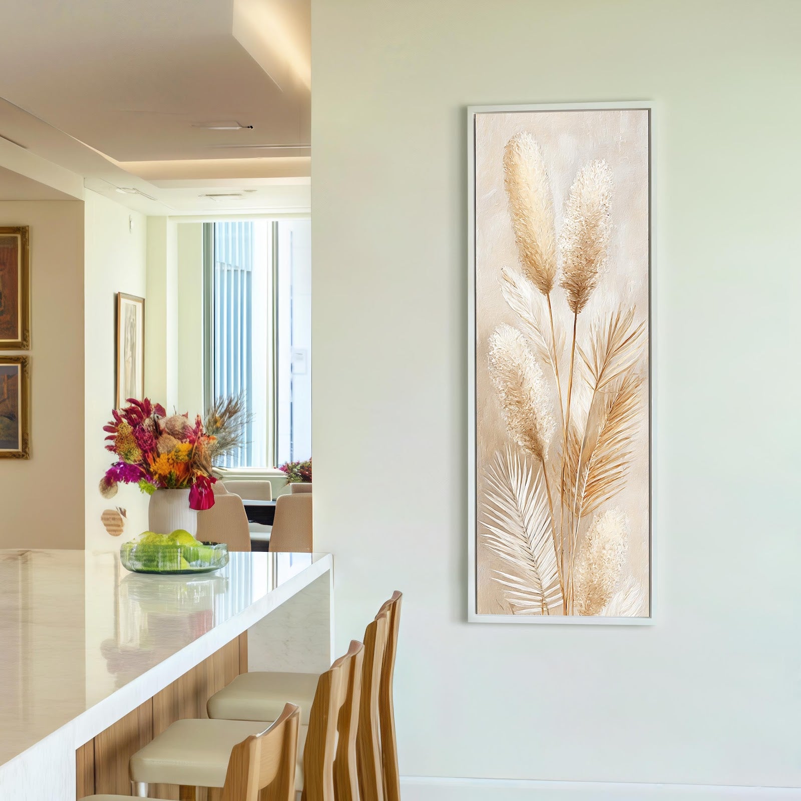 This vertical canvas wall art featuring textured pampas grass in neutral beige tones is displayed in a white floater frame on an off-white wall beside a modern kitchen island.