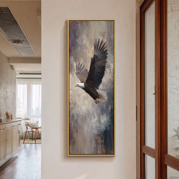 This vertical canvas wall art depicts a bald eagle in flight with a palette of grays, browns, and whites, set against a textured, abstract background and framed in gold.