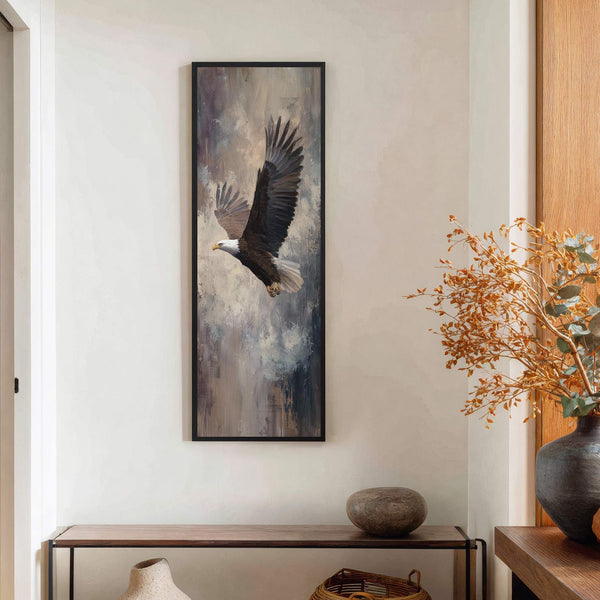 This vertical canvas wall art features a majestic eagle in flight against an abstract background of muted grays and browns, framed in black, displayed on a cream-colored wall above a.