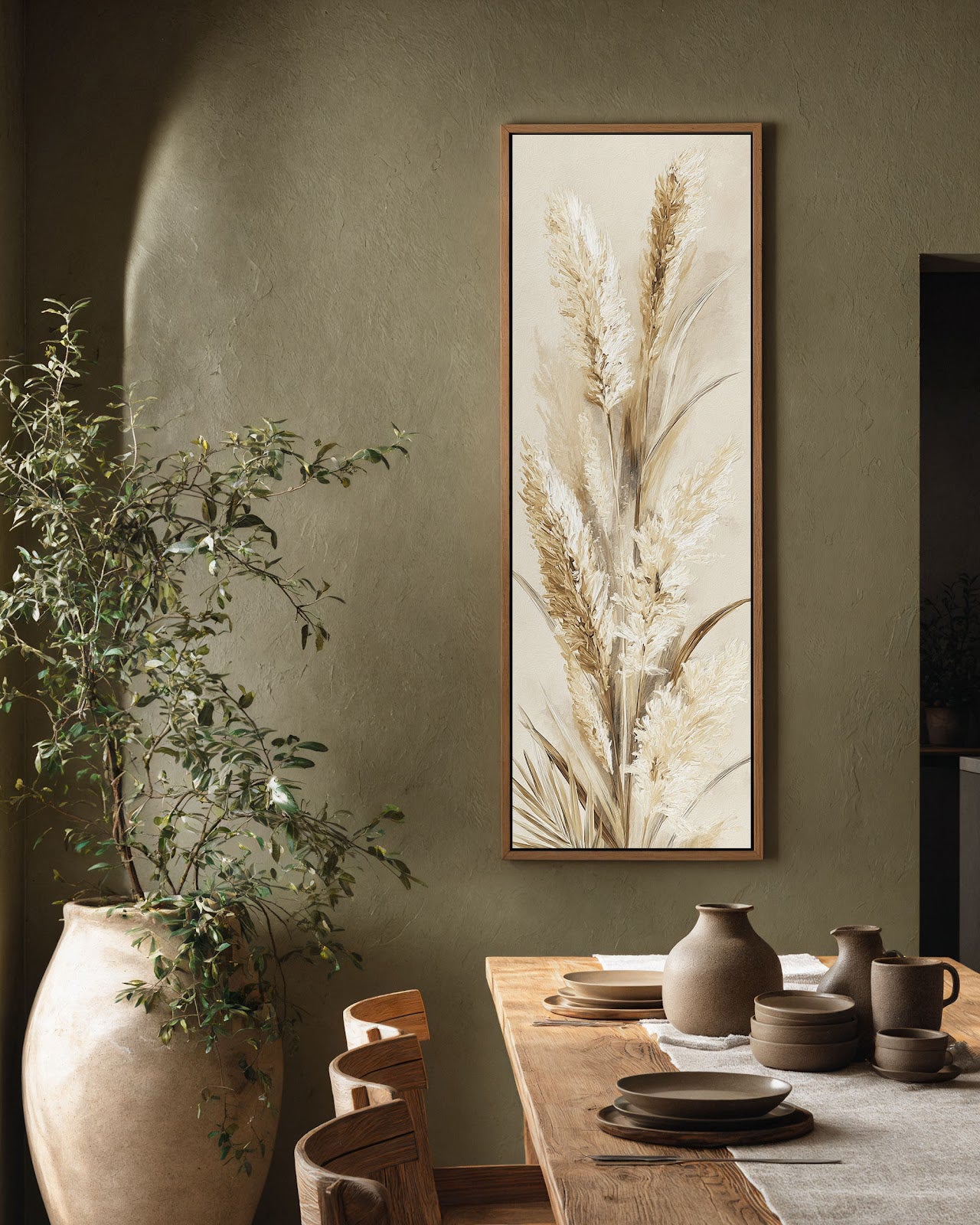 This vertical canvas wall art features textured pampas grass in neutral tones, displayed in an oak floater frame on an olive green wall above a wooden dining table.