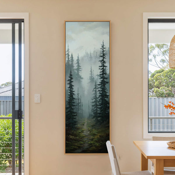 This vertical canvas wall art features a misty forest scene with dark green trees and a path, rendered in a painterly style. It hangs on a cream wall next to.