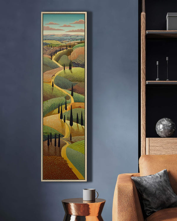 This vertical art print depicts a stylized rolling hills landscape in earthy tones, displayed in a natural floater frame on a dark blue living room wall beside a sofa.
