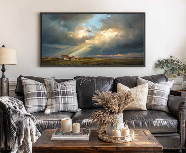 This horizontal canvas wall art features a dramatic landscape painting of a house in a field under a stormy sky with sunbeams breaking through, in a black floater frame. It.