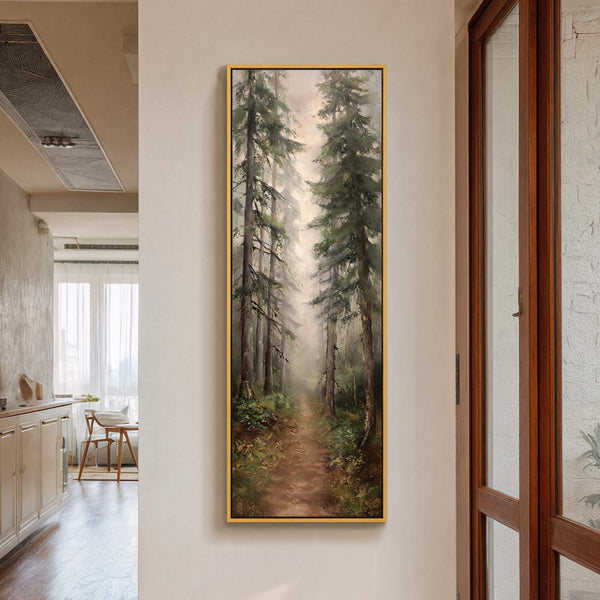 This vertical, impressionistic art print depicts a misty forest path with tall trees and lush greenery in a muted palette, framed in gold, hanging on a neutral wall.