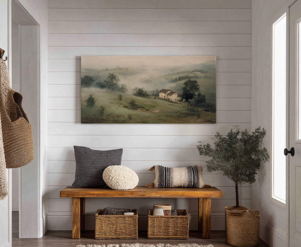 This horizontal canvas wall art features a hazy, impressionistic landscape with rolling hills and a small village, rendered in muted greens and earthy tones. It is displayed on a white.