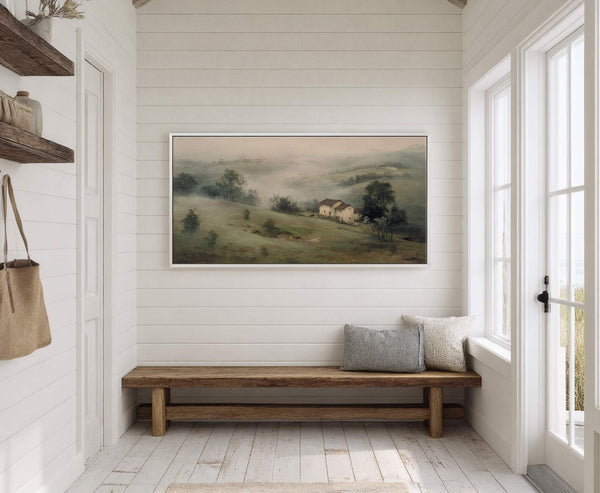 This horizontal canvas print, featuring a misty landscape with houses and trees in a muted green and beige palette, is displayed on a white paneled wall above a rustic wooden.