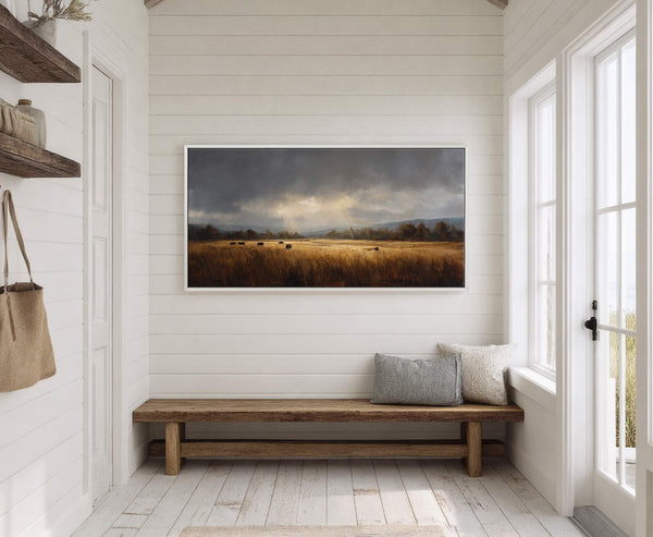 This horizontal canvas wall art depicts a dramatic cloudy sky over a golden field with hay bales, rendered in a painterly style, hanging on a white shiplap wall above a.