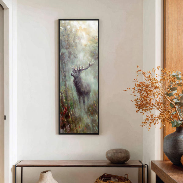 This vertical, impressionistic canvas wall art features a stag amidst misty forest foliage with a muted green and brown palette, framed in black, hanging above a console table on a.