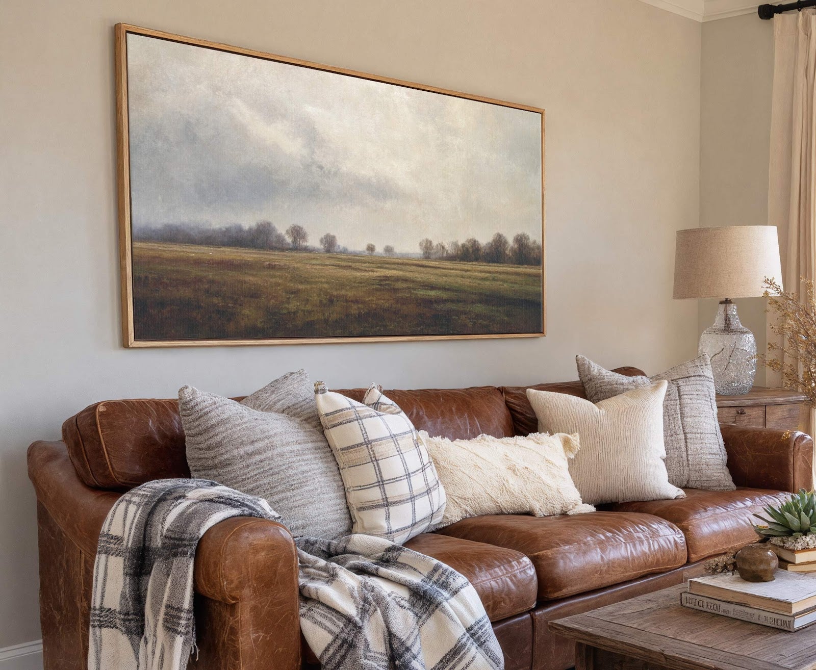 This horizontal canvas wall art depicts a muted landscape with a cloudy sky over fields and trees, rendered in earthy tones. It is framed with a natural wood floater frame.