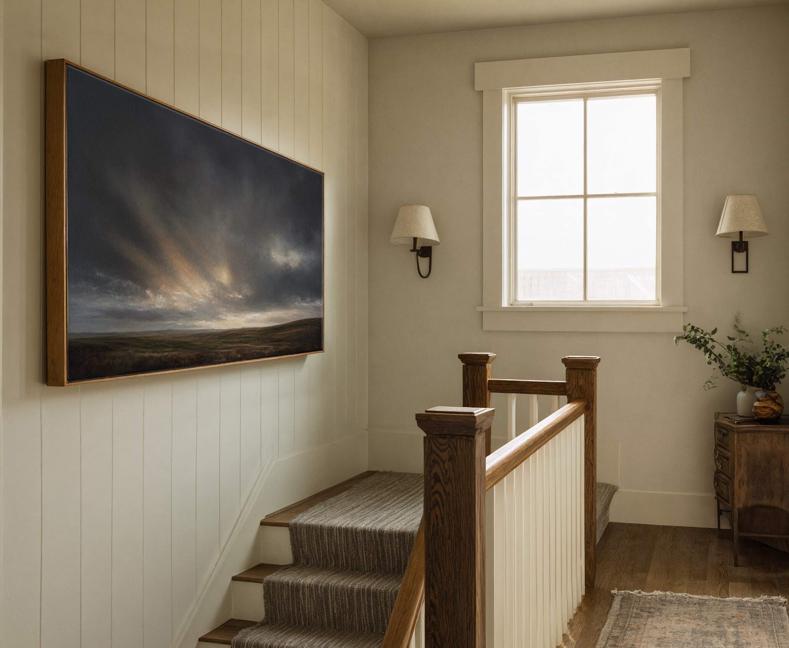 This horizontal canvas wall art depicts a dramatic, moody landscape with dark clouds and rays of light, framed in natural wood, hanging on a wall with vertical paneling next to.
