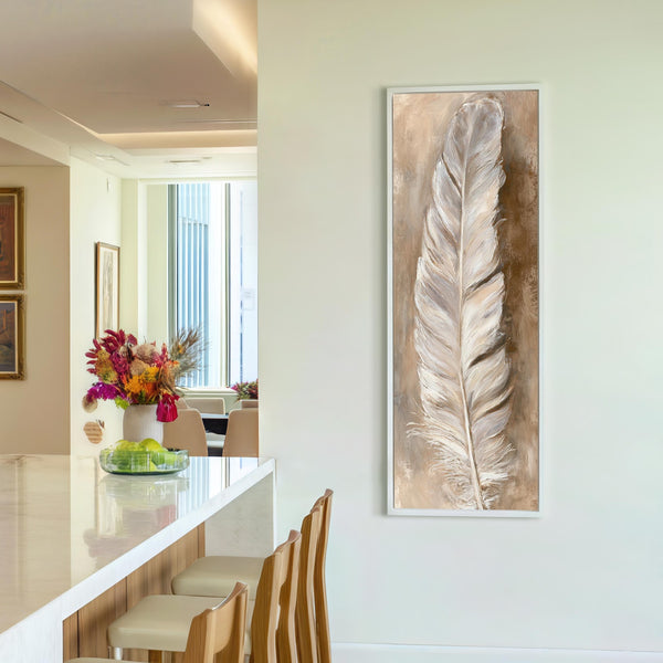 This vertical painting print features an impressionist white feather in a neutral palette, displayed in a white floater frame on a white drywall kitchen wall beside a floral vase.