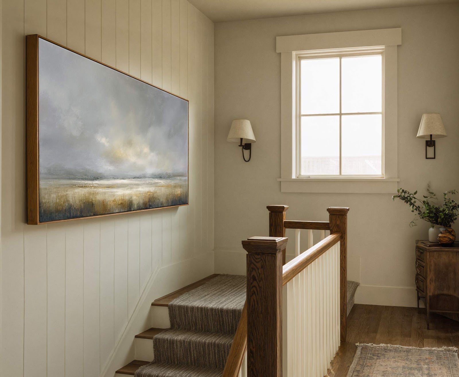 This horizontal canvas print features an abstract landscape with a muted gray and gold palette, set in a hallway with paneled walls and a wooden staircase railing.