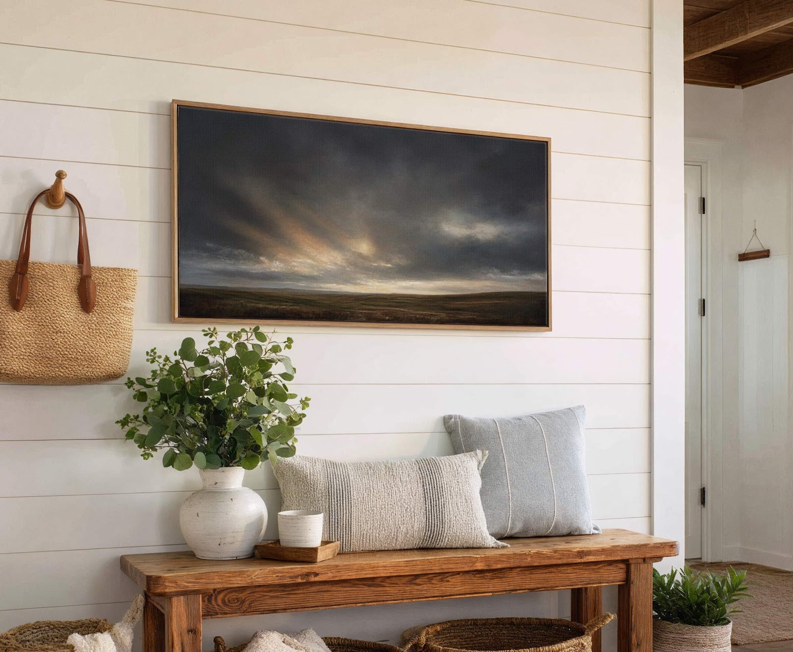 This horizontal canvas wall art displays a dramatic, moody landscape with dark, stormy clouds breaking to reveal soft rays of sunlight over rolling hills, rendered in a realistic painterly style.