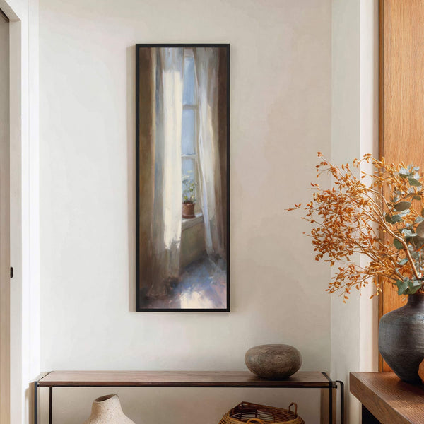 This vertical canvas wall art features a painterly impression of light streaming through a window with white curtains and a small potted plant, framed in black, hanging above a console.