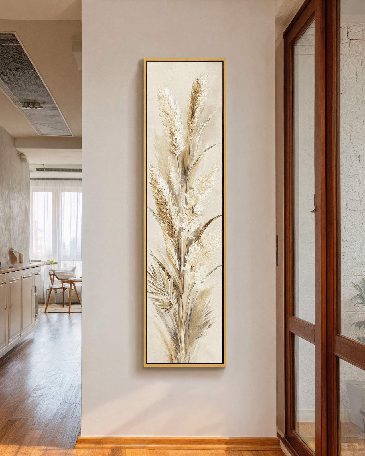 This vertical canvas wall art depicts textured pampas grass in a neutral palette, displayed in a gold floater frame on a white drywall hallway wall near a wooden door.