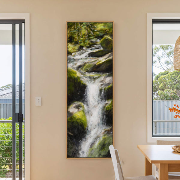 This vertical canvas wall art features a lush, impressionistic painting of a waterfall cascading over mossy rocks, with a palette of vibrant greens and whites, framed in natural wood and.