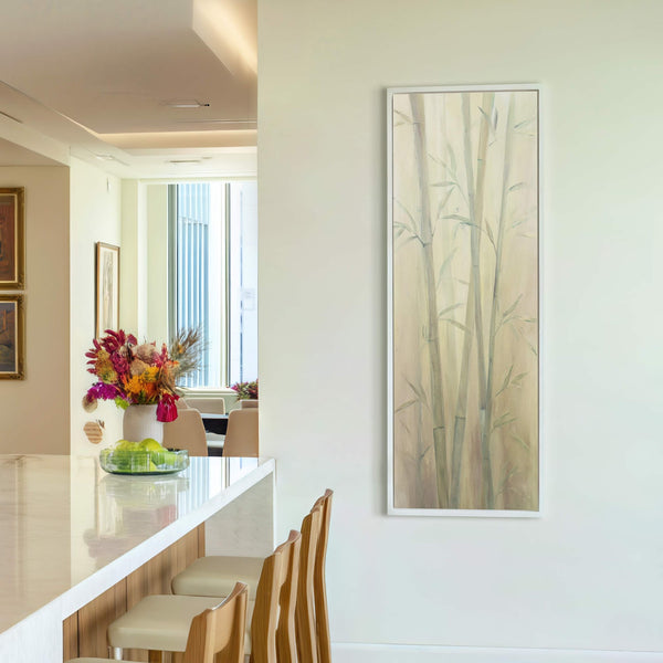 A vertical canvas print with a soft palette depicts bamboo stalks in a painterly style, framed in white and displayed on a pale wall next-to-white wall.