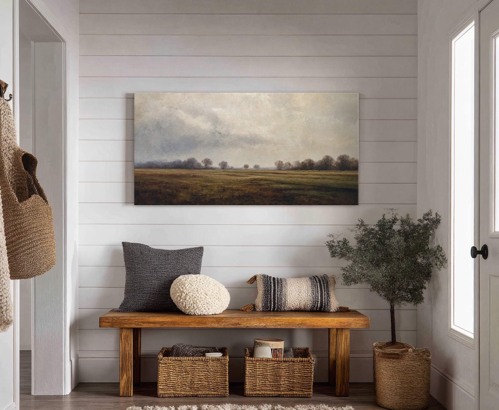 A horizontal, stretched canvas wall art print depicts a serene landscape with a muted palette of greens, browns, and grays, showcasing a field and trees under a cloudy sky, displayed.