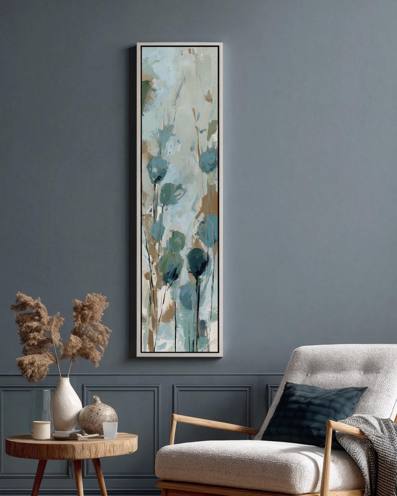 Teal abstract wildflower canvas art in black floating frame above accent chair in modern living room with blue-gray walls, vertical botanical print