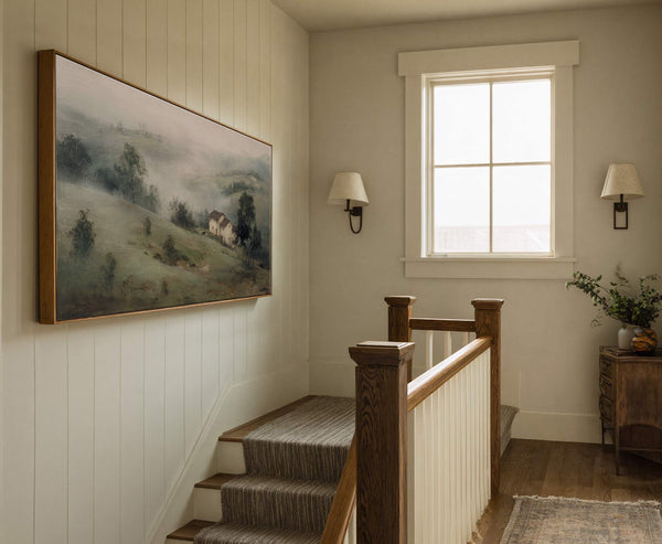 This horizontal canvas wall art features a misty landscape with a small house, rendered in a muted green and gray palette with a painterly style. It is framed in natural.