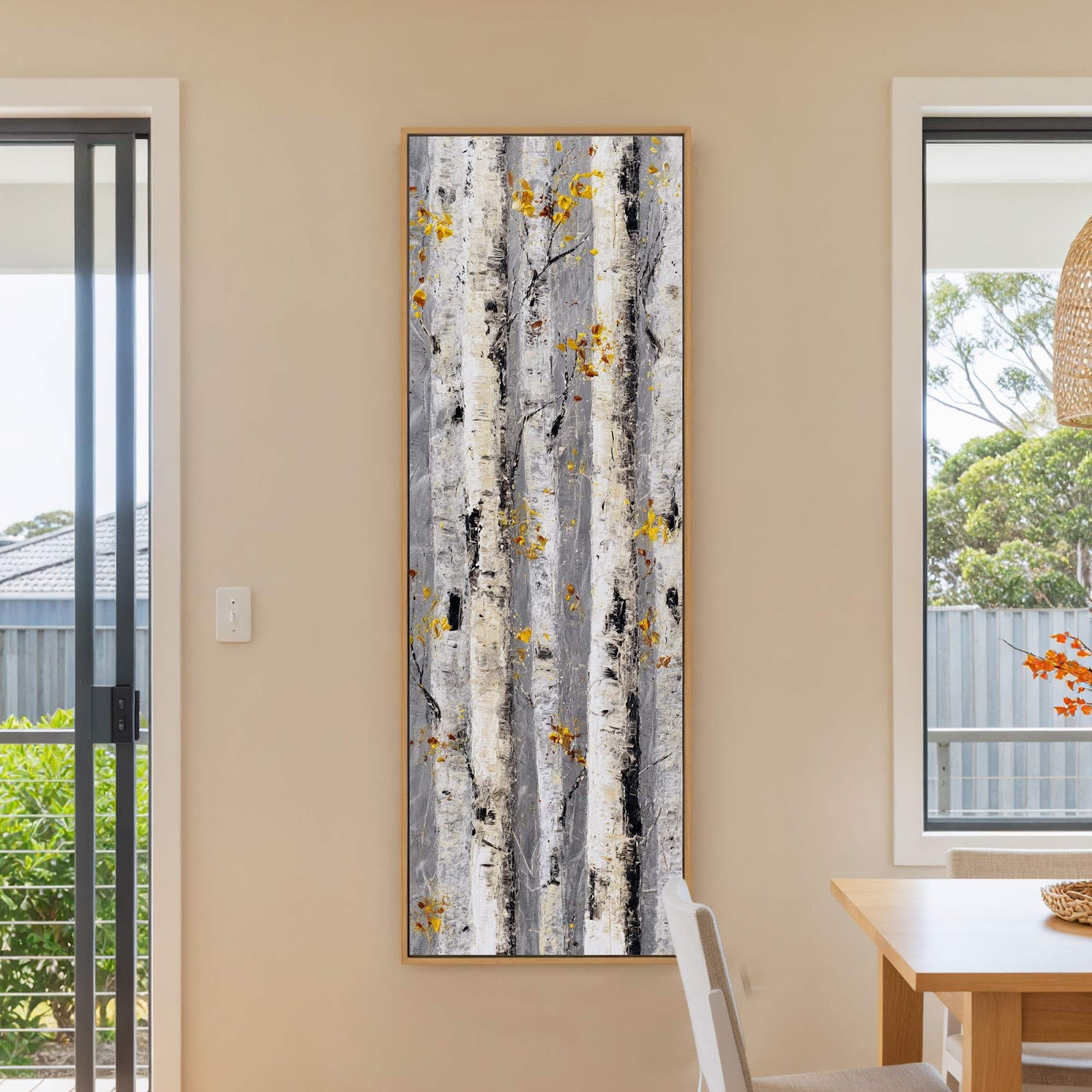 This vertical canvas wall art features an impressionistic style painting of birch trees with yellow leaves, framed in a natural wood floater frame and hung on a light beige wall.