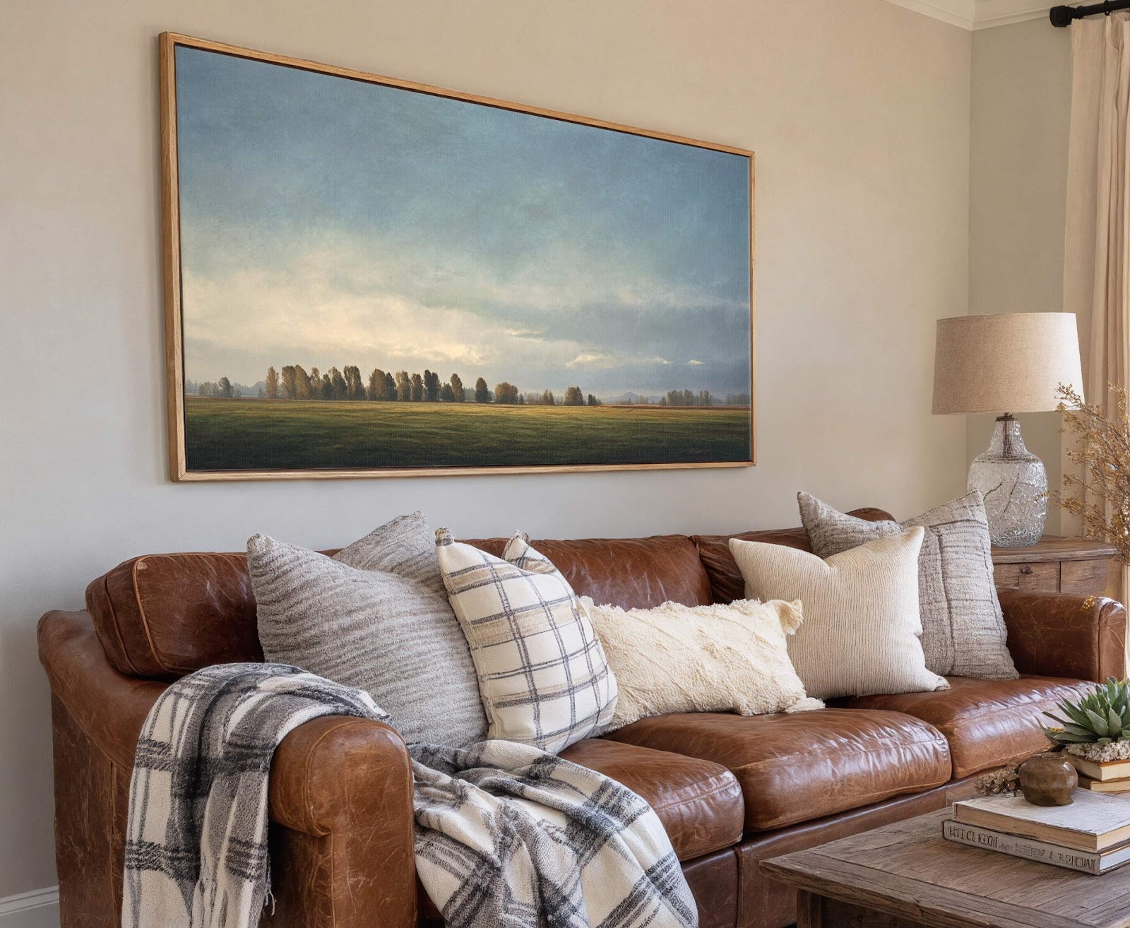 This horizontal canvas wall art displays a pastoral landscape with trees and a grassy field under a cloudy sky, rendered in soft, muted tones. It is displayed above a brown.