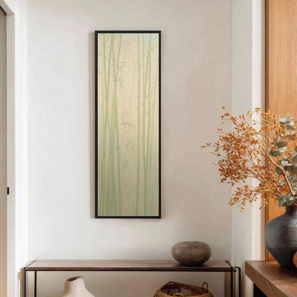 A vertical, impressionistic art print with a soft palette depicts bamboo stalks against a pale yellow background, framed in black and displayed in a room with a narrow console table.
