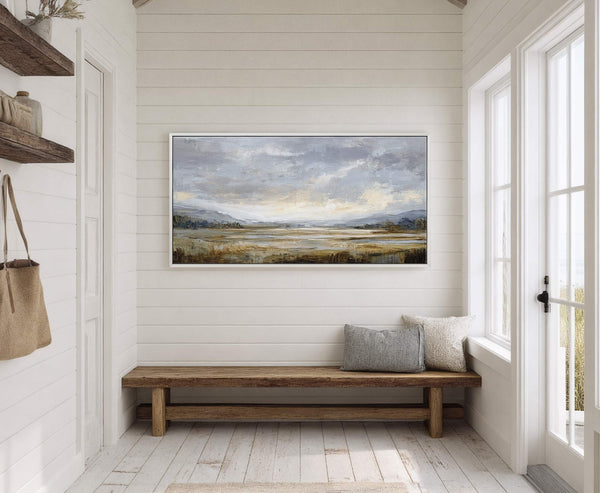 This horizontal canvas wall art features an abstract landscape in a muted palette of grays, blues, and earthy tones, displayed in a white floater frame on white wood-paneled walls above.