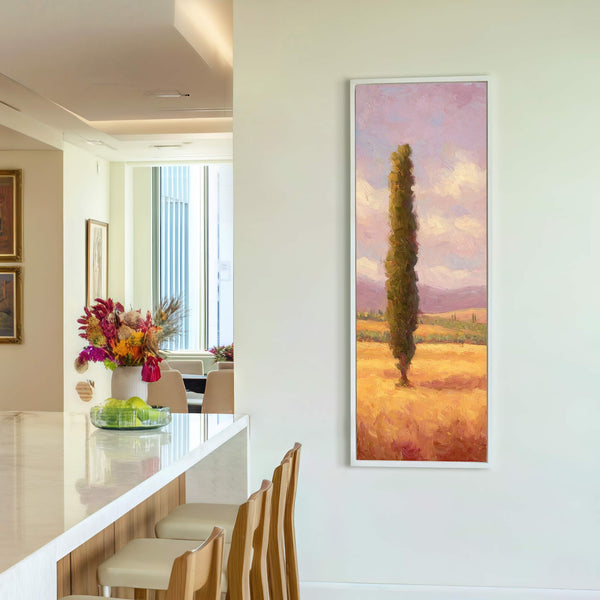 This vertical canvas print features an impressionist landscape with a cypress tree in a golden field under a pink and blue sky, framed in white and displayed on a white.