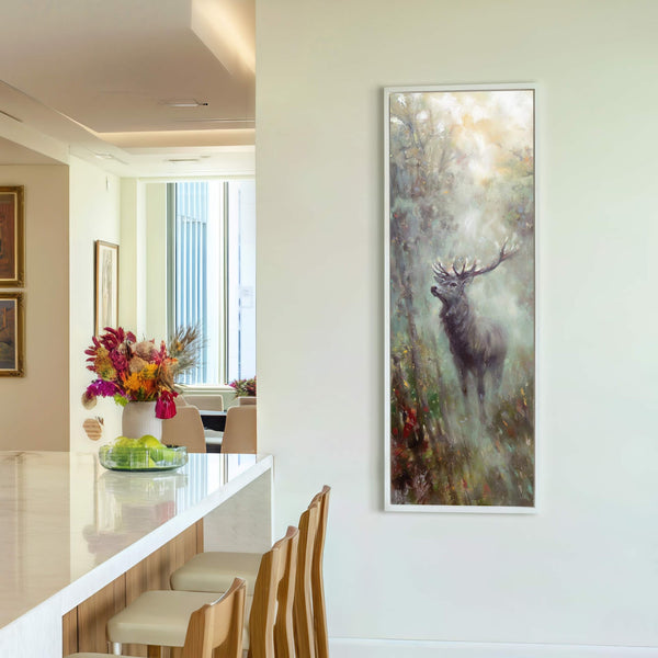 A vertical canvas print features a stag in a misty forest with a muted color palette, displayed on a pale wall above a bar counter with bar stools. The art.