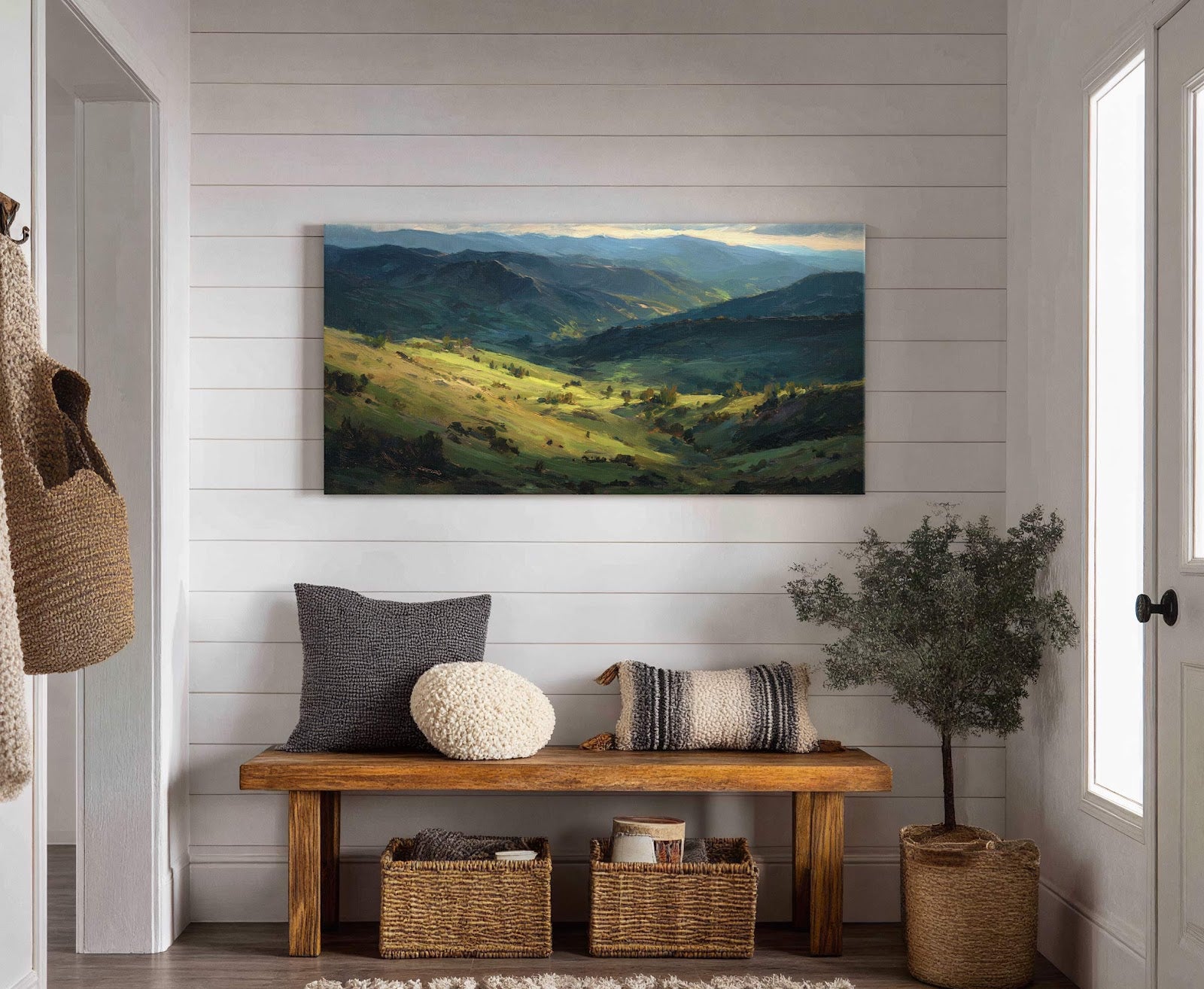 This horizontal canvas wall art depicts a valley landscape in an impressionistic style with a palette of deep greens and blues, set above a wooden bench with pillows and baskets.