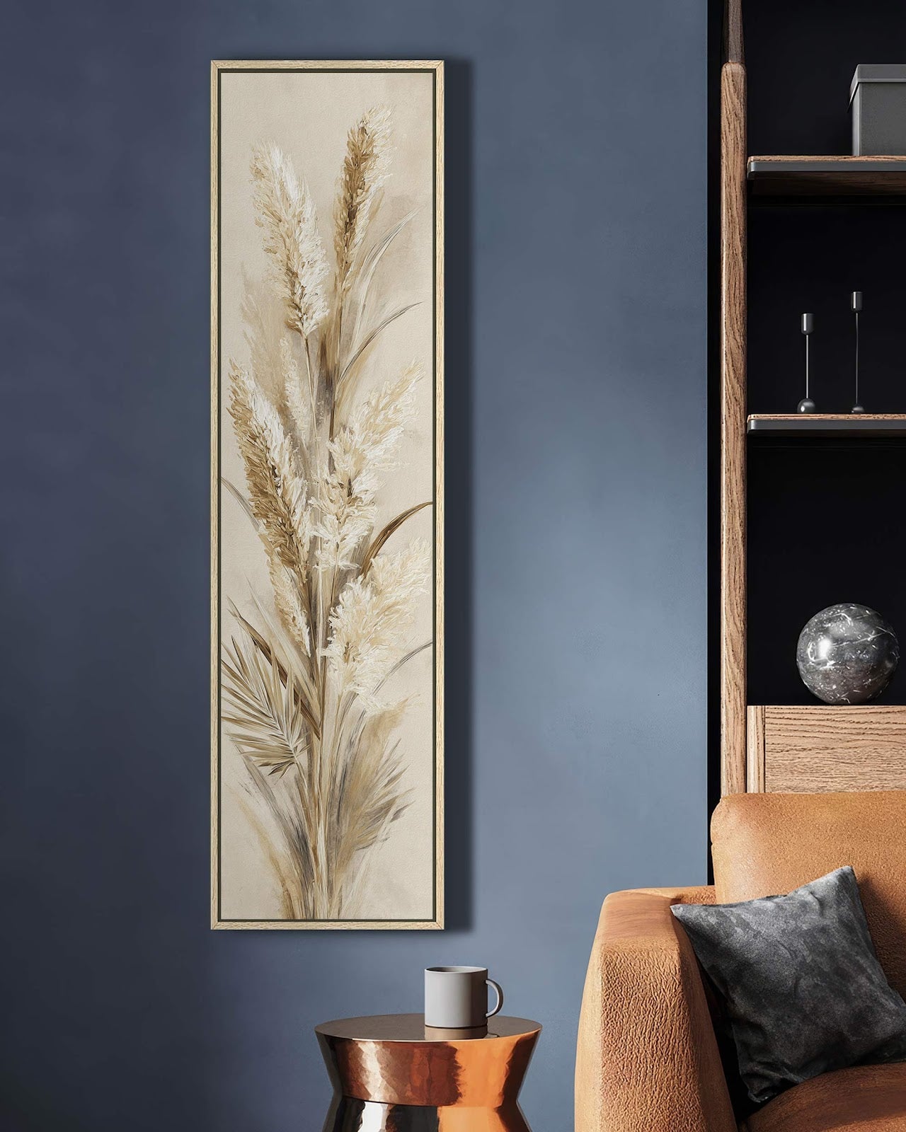 Featuring neutral pampas grass in a painterly style, this vertical canvas wall art with an oak floater frame hangs on a dark blue wall beside a tan sofa.