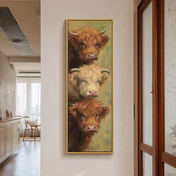 This vertical canvas wall art features a painterly style with a warm, earthy palette showcasing three Highland cows stacked vertically, displayed on a white wall next to a wooden-framed window.