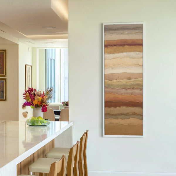 This vertical canvas wall art features an abstract style with a palette of earthy browns and beiges, depicting layered geological strata on a white wall, with bar stools and a.